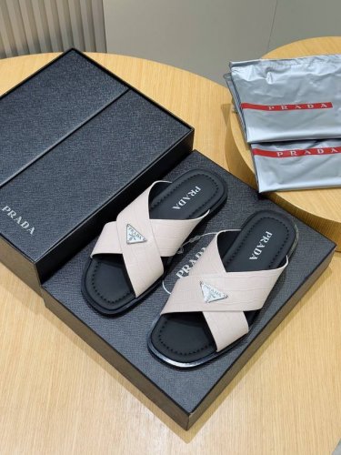 Prada家最新拖鞋官网同步这款拖鞋以品牌独特的标志性Saffiano牛皮打造，品牌徽标跃于双饰带，品牌格调一览无余。牛皮和真皮大底赋予男性优雅魅力与功能性设计