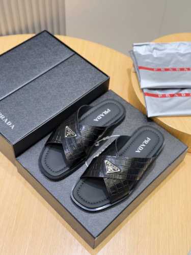 Prada家最新拖鞋官网同步这款拖鞋以品牌独特的标志性Saffiano牛皮打造，品牌徽标跃于双饰带，品牌格调一览无余。牛皮和真皮大底赋予男性优雅魅力与功能性设计
