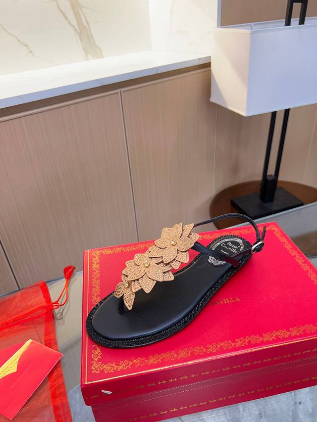 Rene Caovilla芮妮 乔薇拉 Rc 年春季新品 Varie丁字凉鞋糅合黑色的隽永优雅与平底鞋的百搭实穿，时尚鞋款缀有三个盛放的花朵，散发浪漫魅力，是漫