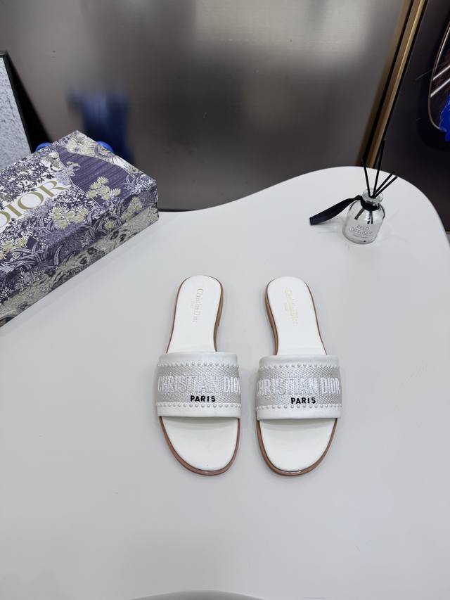 橙子出厂价P Dior 迪奥春夏新款 珍珠刺绣平底拖鞋 休闲凉拖 一字拖 这款D-Lane凉拖彰显经典风格。黑色牛皮革鞋面，展示镂空藤格纹图案，饰以金色饰面金属