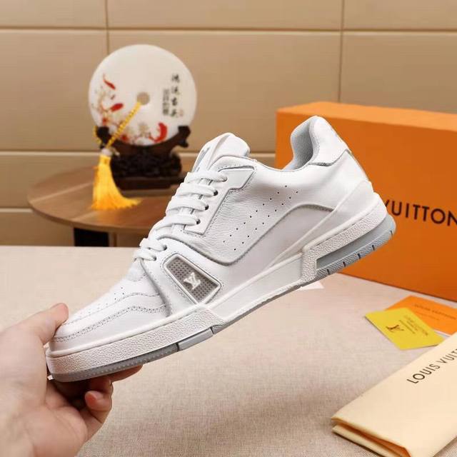 Virgil Abloh 以古着篮球鞋为蓝本，创作 Lv Trainer 运动鞋。粒面小牛皮鞋舌呈现纯净色调，设计师手写体路易威登标识压印一侧，后部 #54 标