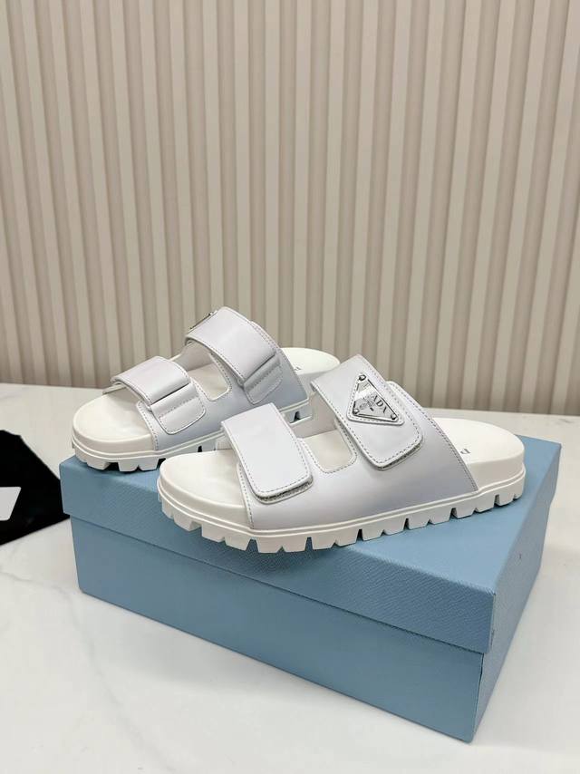 P直销 Prada2025最新款普拉达拖鞋，拖鞋于极简主义设计中展露柔美气息。三角形徽标装饰引人注目。 鞋面小牛皮金属三角形徽标 2厘米橡胶鞋底 凹凸鞋底花纹