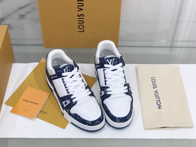 本款 Lv Trainer 运动鞋取材 Monogram 压纹粒面小牛皮和丝滑小牛皮饰边，展现路易威登男装艺术总监 Virgil Abloh 对复古篮球鞋的灵感