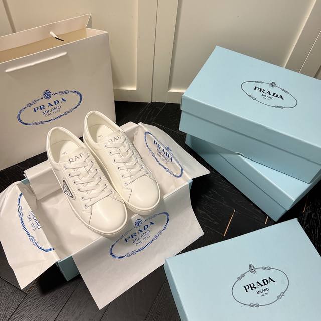出厂： Prada 普拉达新款休闲鞋板鞋 三角标小白鞋 小红书爆款，这款运动鞋鞋舌、轻质橡胶鞋底和脚踝皆饰以Prada徽标的多种重释元素，侧面的标志性涂珐琅三角
