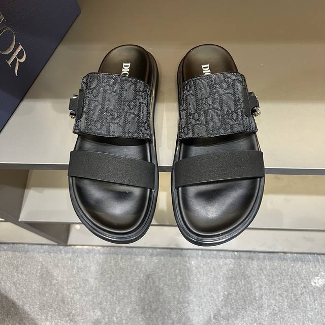dior 男士凉鞋拖鞋。展现 Dior 高订风格设计。迪奥灰绒面革饰带点缀以铝质 Dior 搭扣提升格调。搭配舒适的同色调凹口鞋底，可与短裤或牛仔裤轻松搭配，打