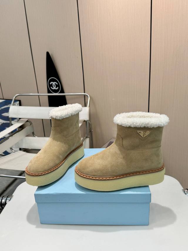 Prada 厚底雪地靴，时尚与温暖并存。 经典三角标，彰显品牌魅力。内里和垫脚全羊毛，保暖效果满分，让你在寒冷冬日也能暖意融融。4 厘米厚的 Tpu 鞋底，增高